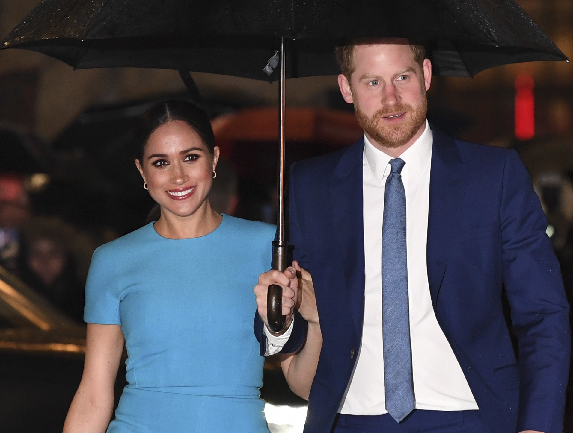 Meghan Markle and Prince Harry walking underneath an umbrella