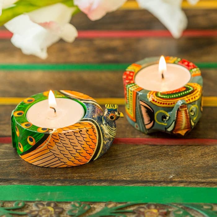 A peacock and elephant tealight holder with candles in them