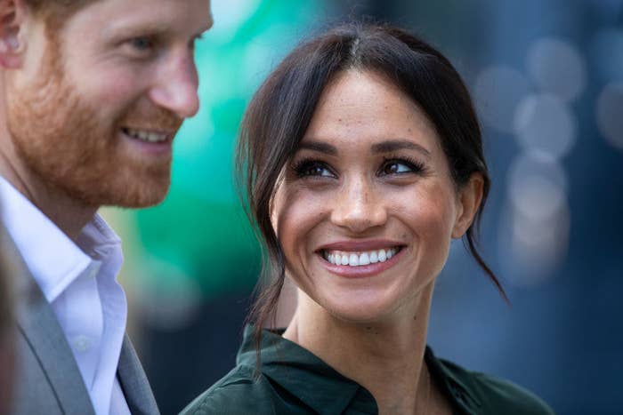 Meghan smiling big and looking up at Harry