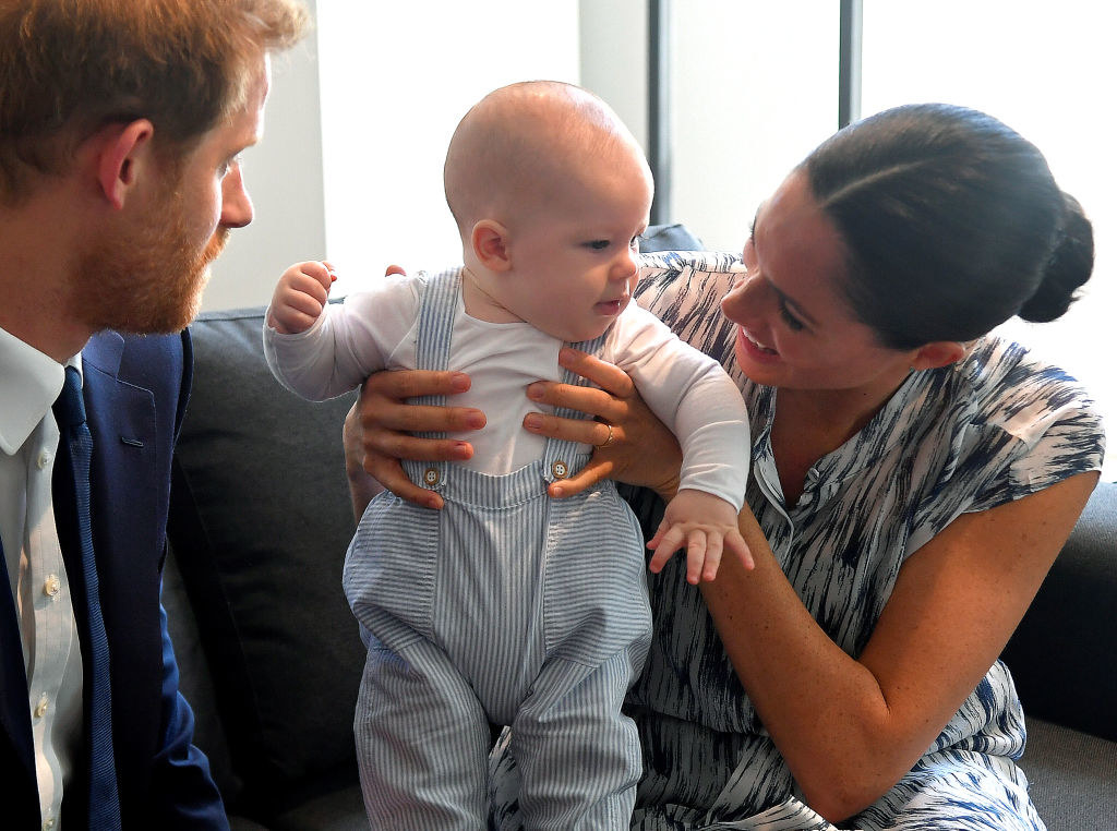 Meghan smiling and holding up Archie