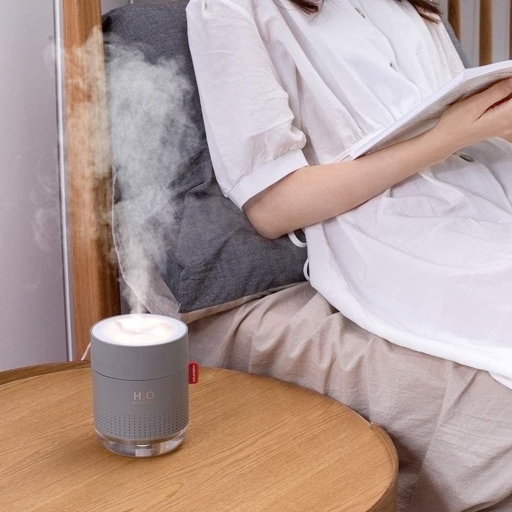 A person sitting in bed with a small humidifier beside them
