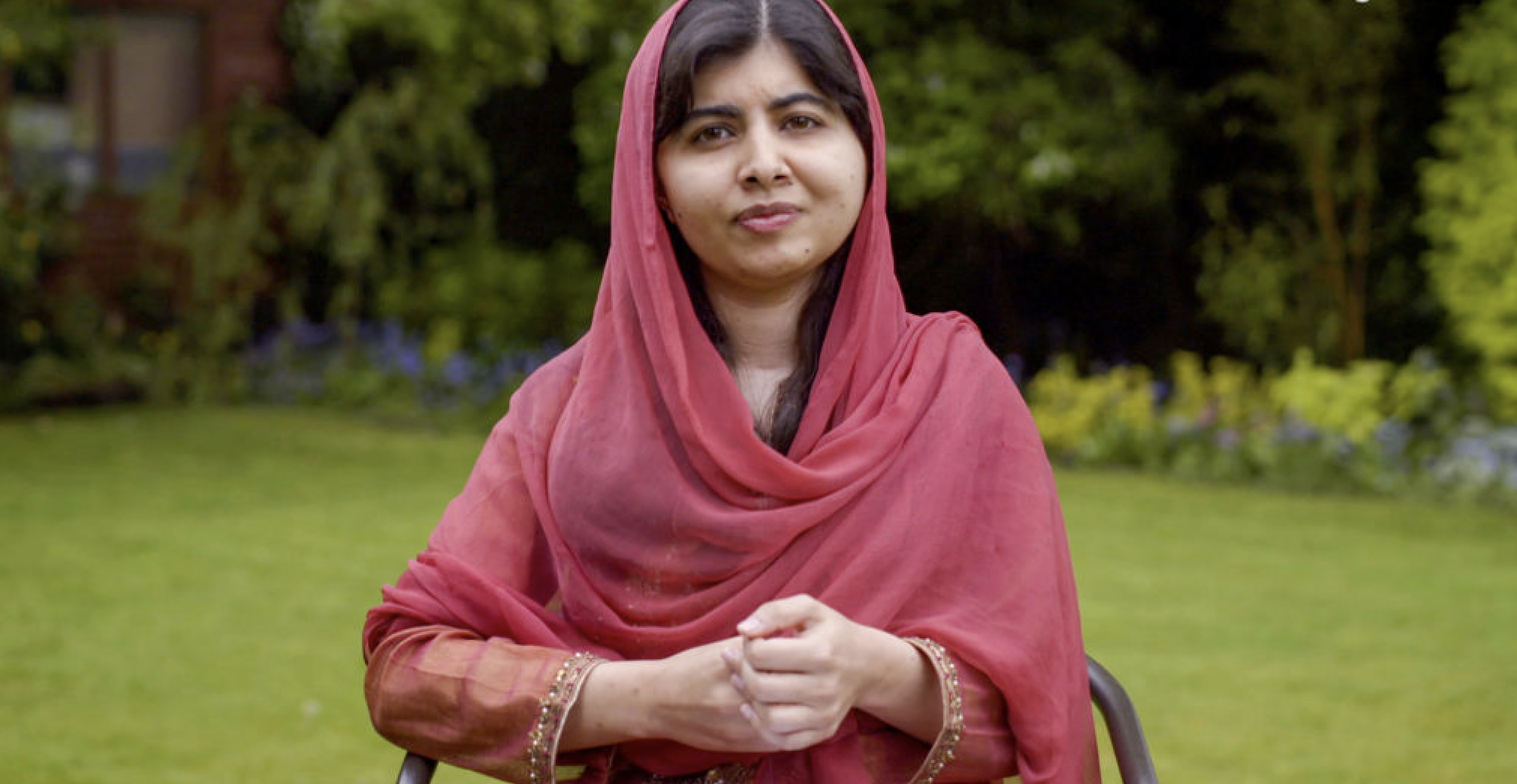 Malala sitting outside in a chair on the grass