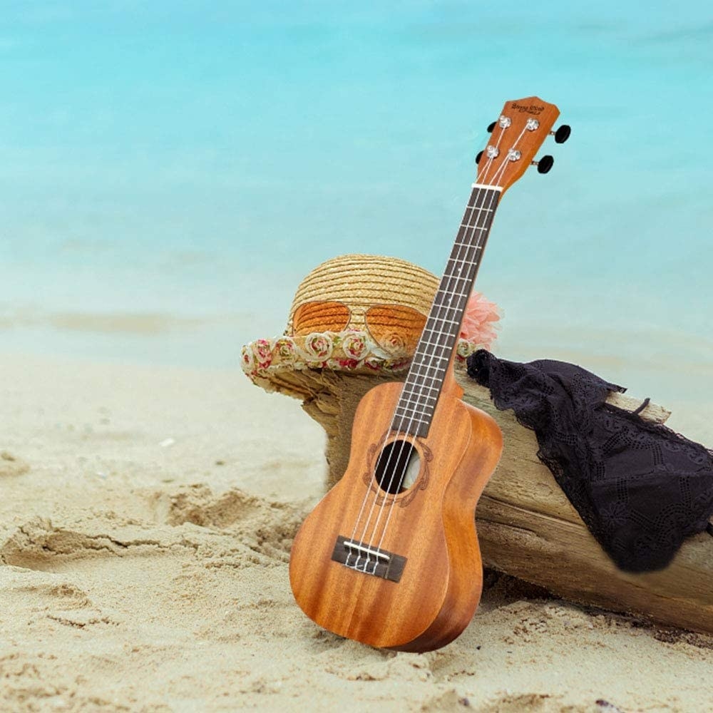 A ukulele leaning against a log on the beach