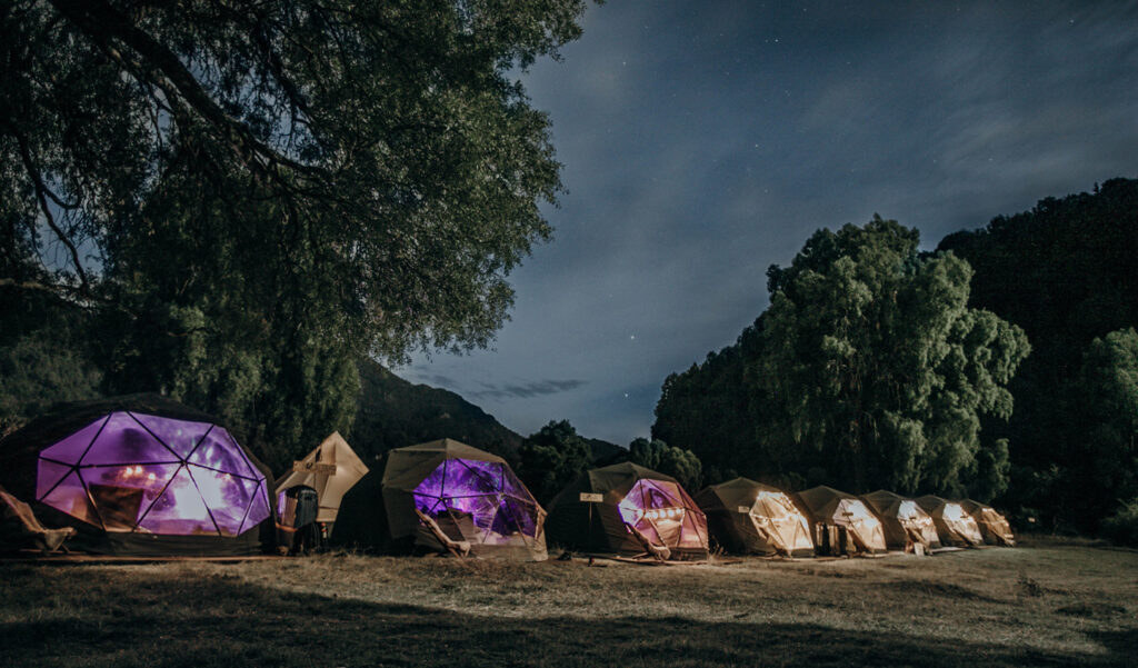 A row of geometric tents in a field at night