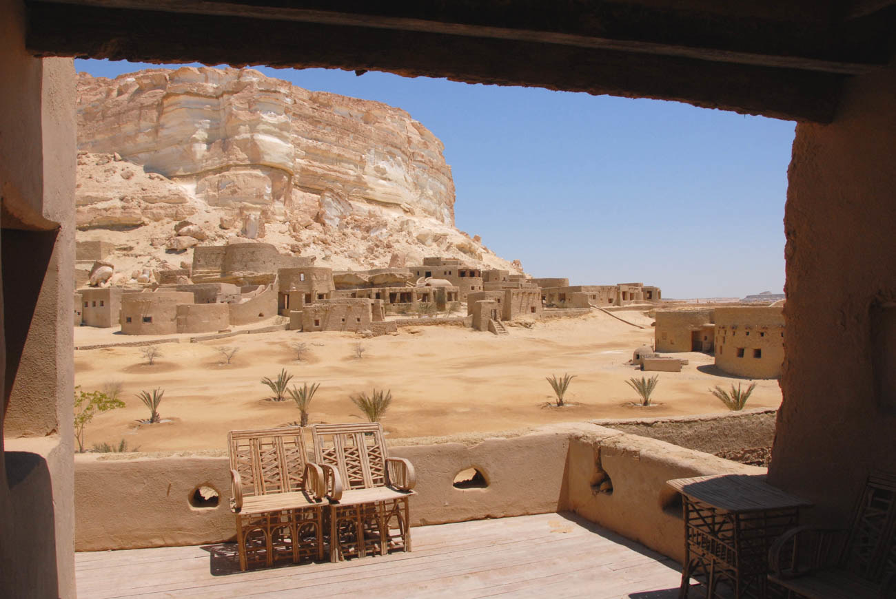 Looking out the window of a hotel room at the desert, the walls and furniture all blend in with the landscape
