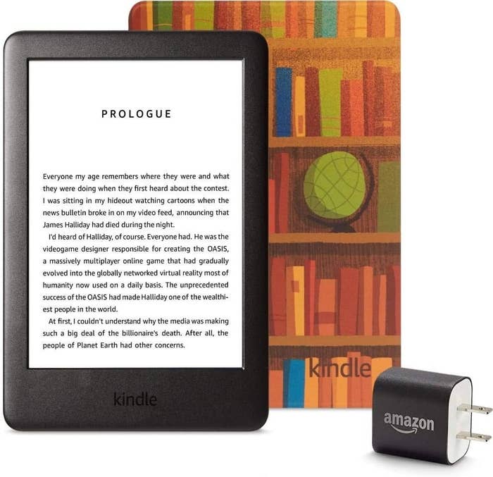 The kindle, the cover covered in an illustration of bookshelves, and a wall charger