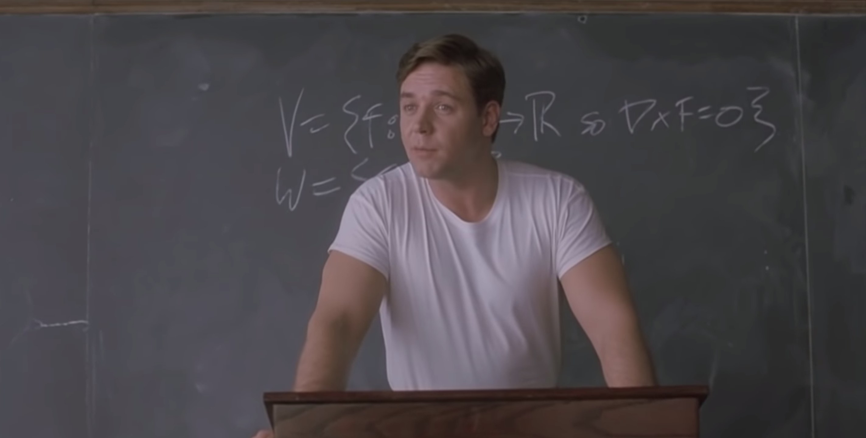 A young Russell Crowe standing in front of a chalkboard 