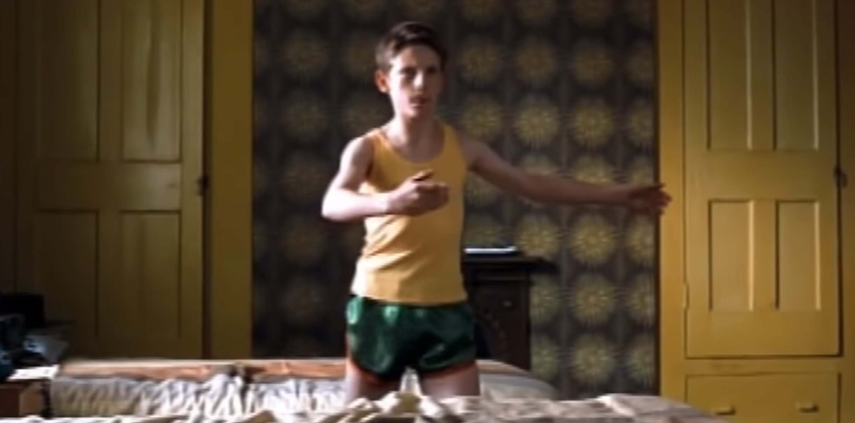 A young boy wearing gym clothes doing a dance move