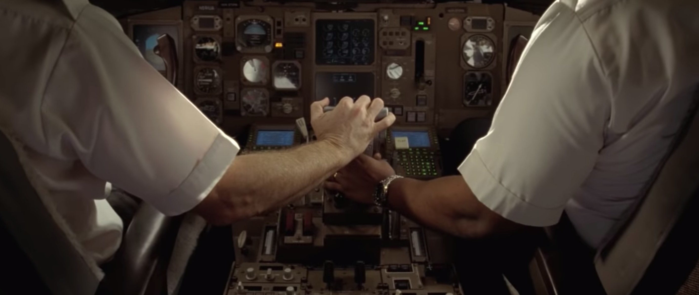 Two pilots holding hands while controlling a plane in the cockpit