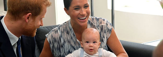 Meghan laughing and holding baby Archie beside Prince Harry