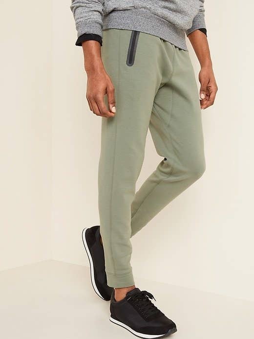 Model wearing the joggers in money maker green with a grey sweatshirt and black sneakers