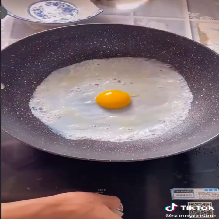 An egg yolk resting on top of an egg white in a skillet.
