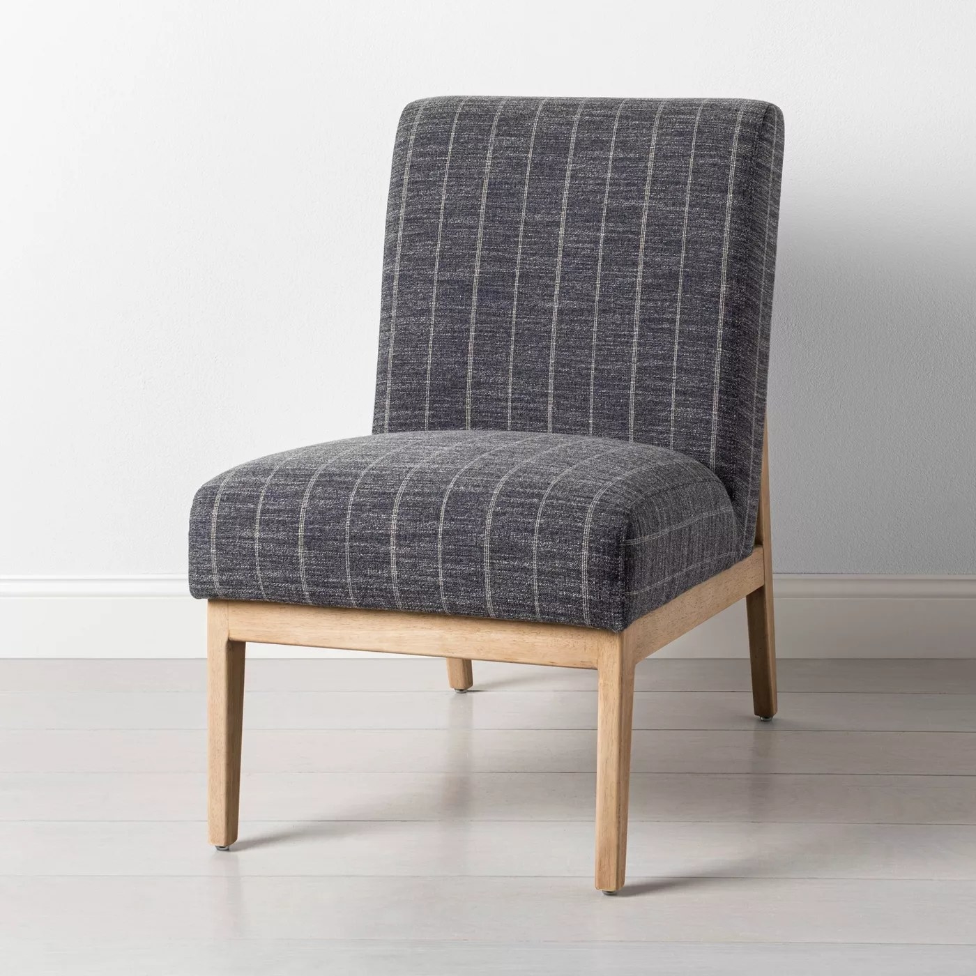 The armless chair with a gray striped fabric and light wood frame