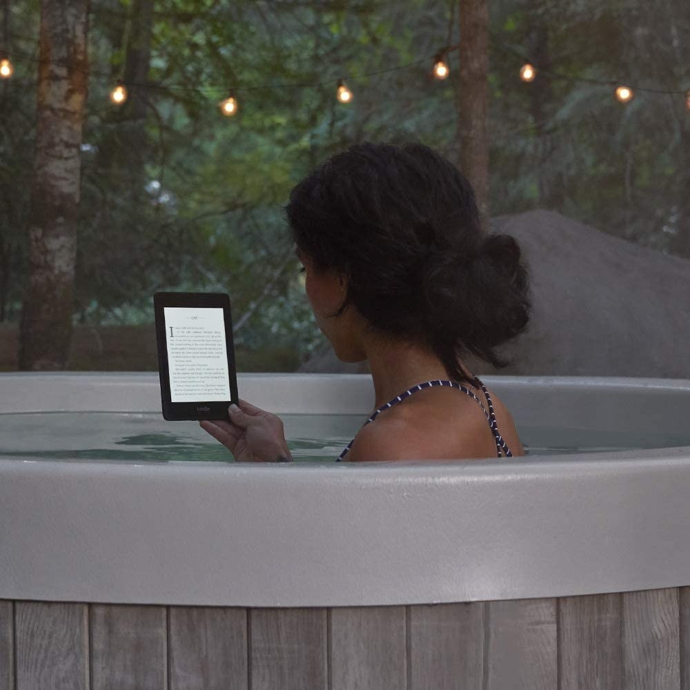 A person reading a Kindle in a hot tub