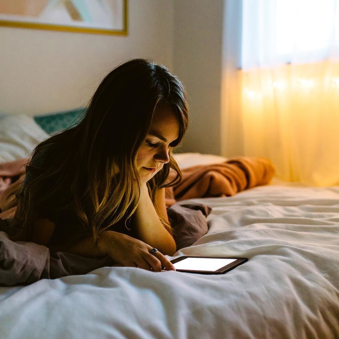 A person reading a Kindle in bed