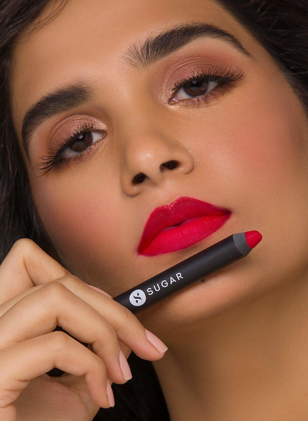 A Model wearing the lipstick. She&#x27;s holding up the lipstick below her lip.