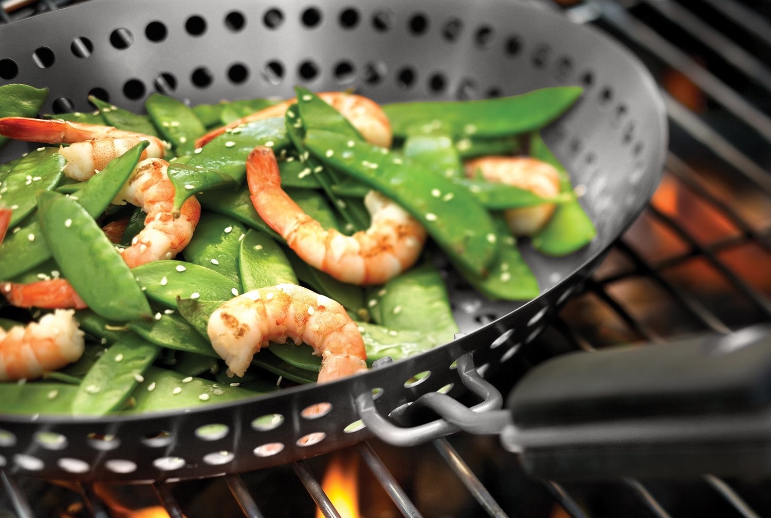 Shrimp and beans being cooked on a grill in a pan with perforations