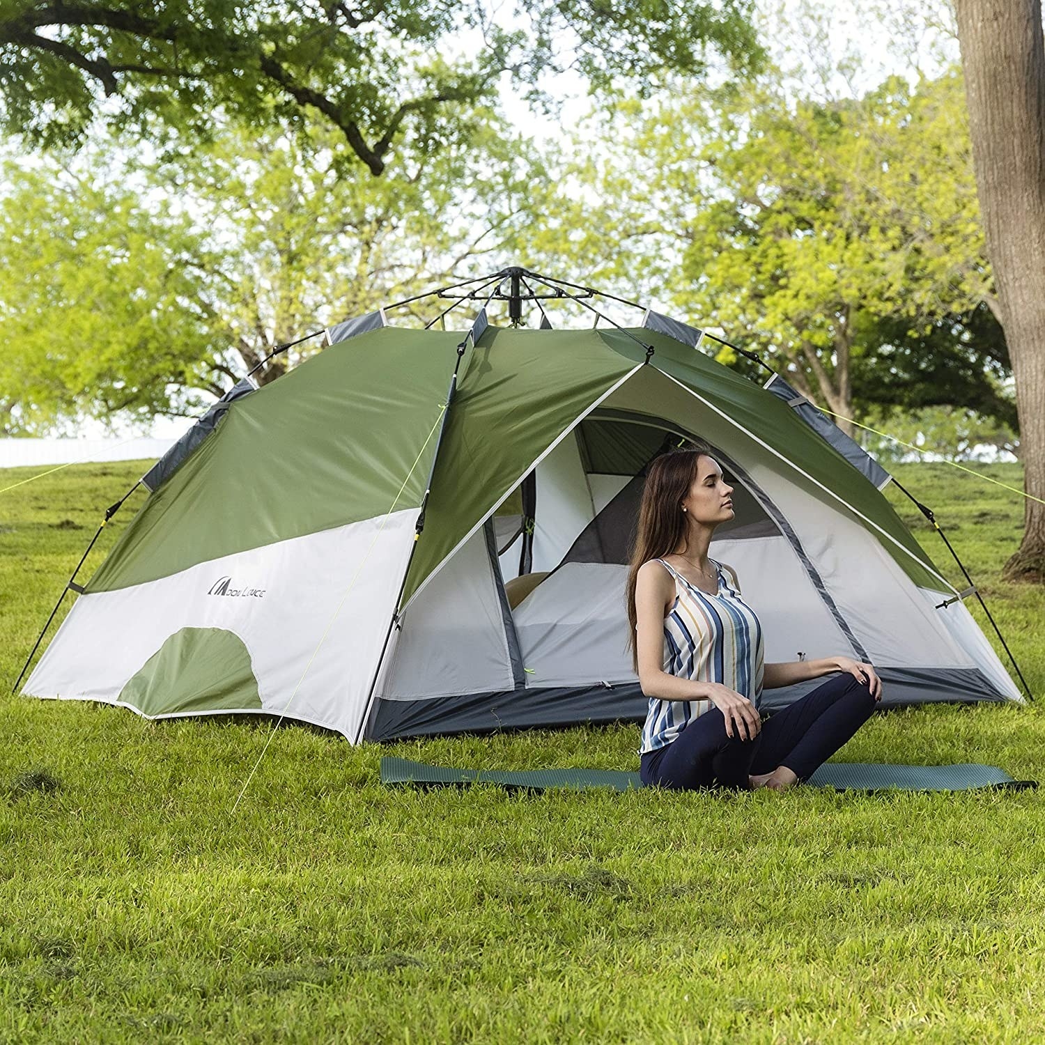 Person sitting outside green and white pop up tent 