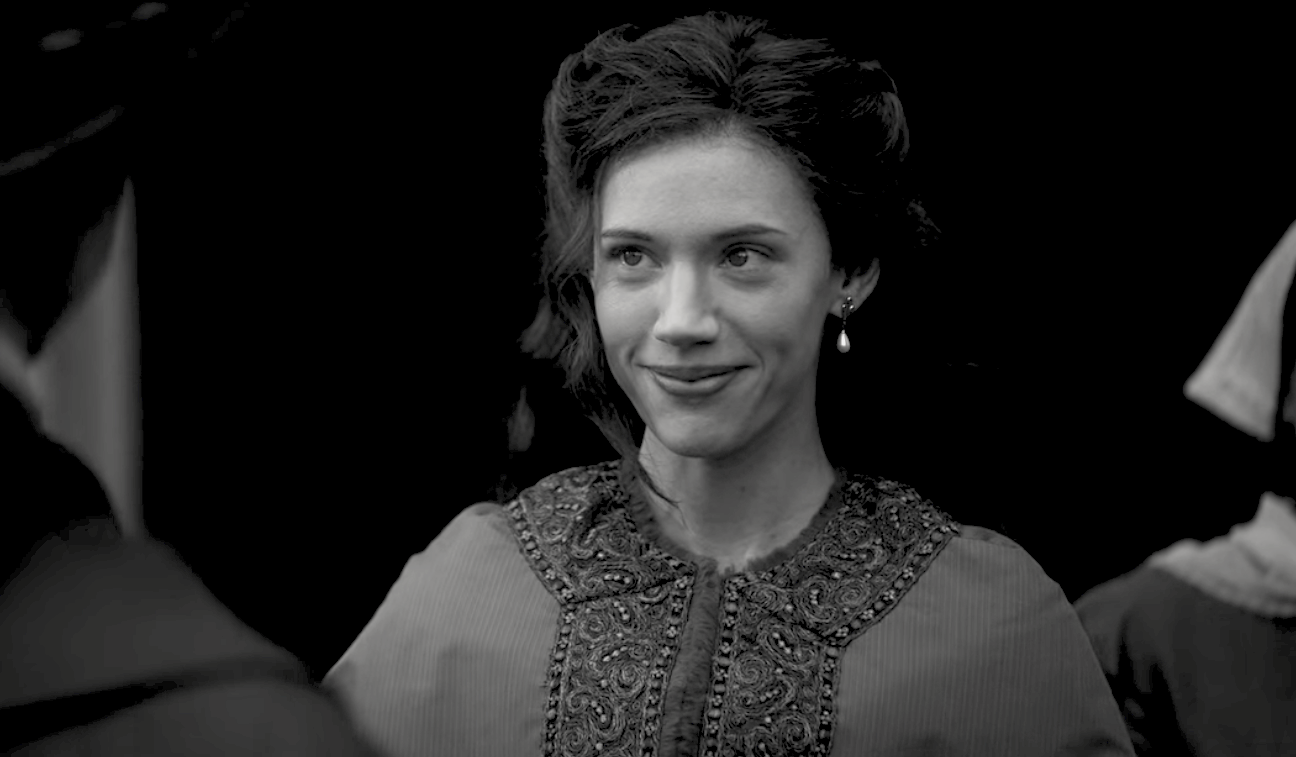 A black and white image of a woman smiling slightly at someone off screen