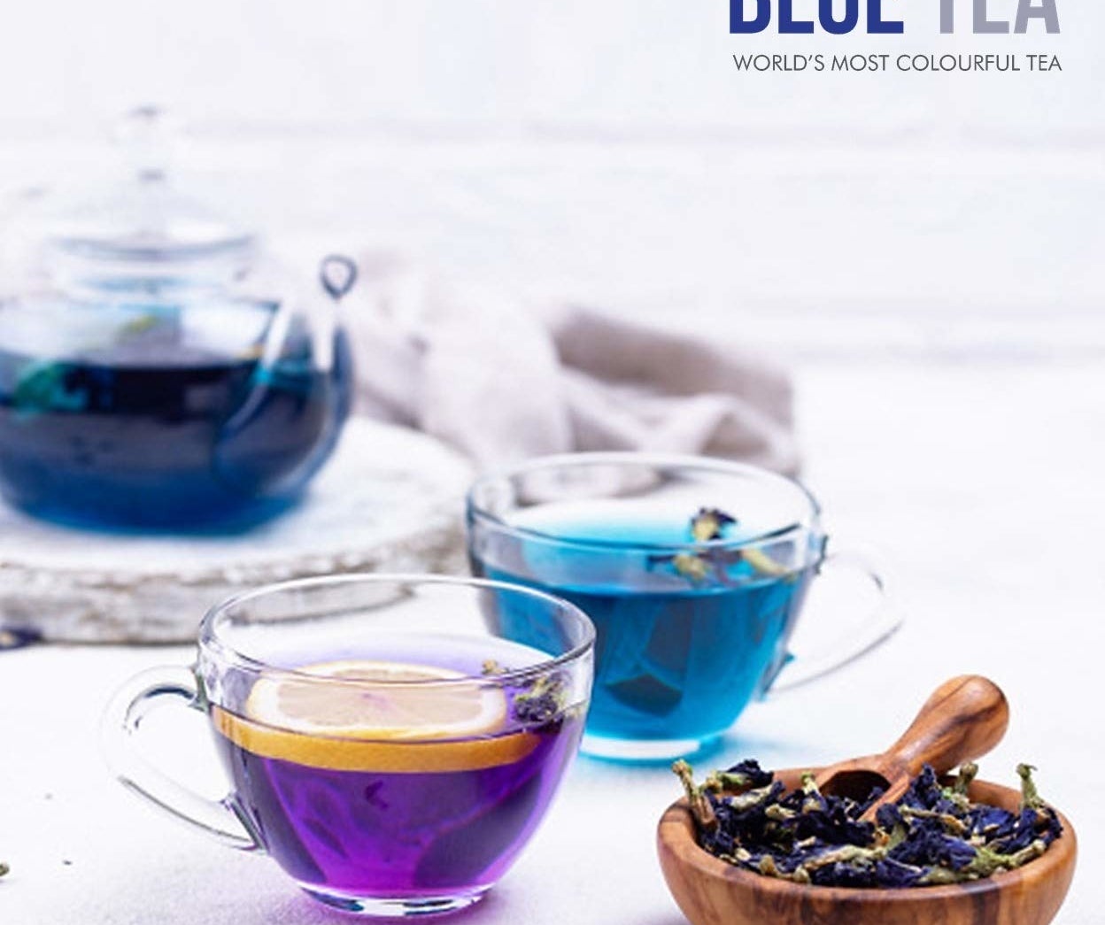 A transparent teacup with blue tea and one with lemon turning the tea purple.