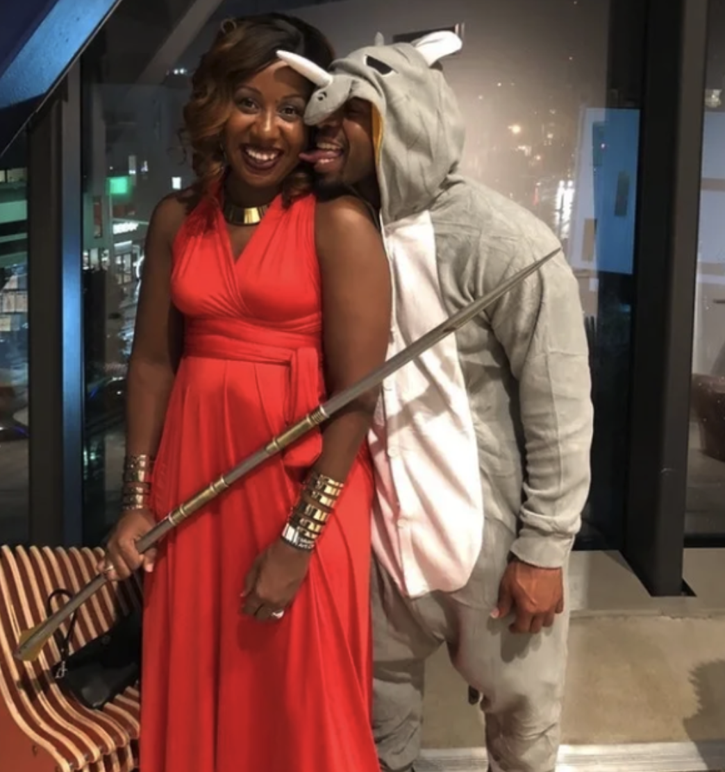 One person as Okoye, in a red dress with a weapon, and another wearing a rhino onesie