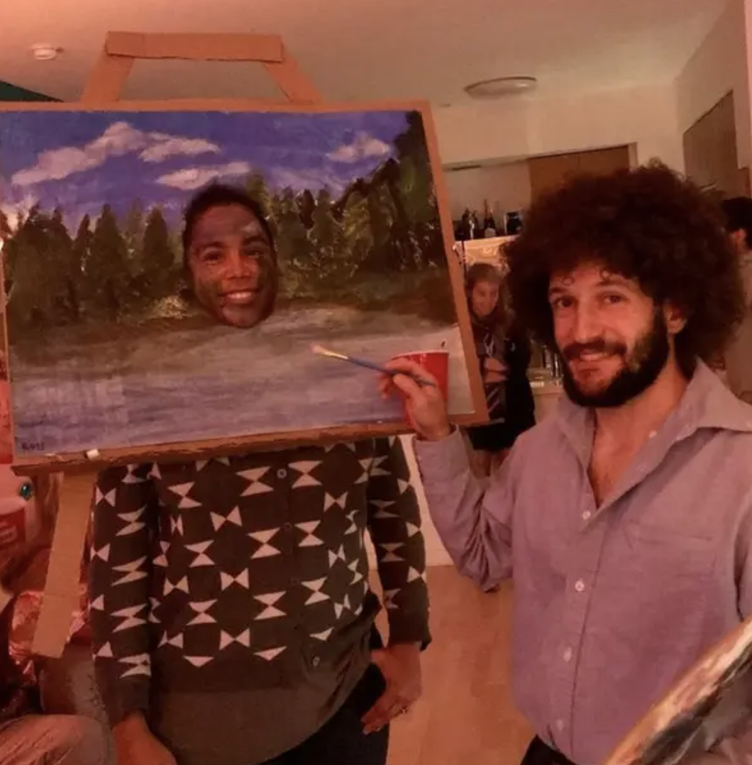 Someone dressed as Bob Ross, and another dressed as a painting of nature with a hole cut out in the middle where their face is