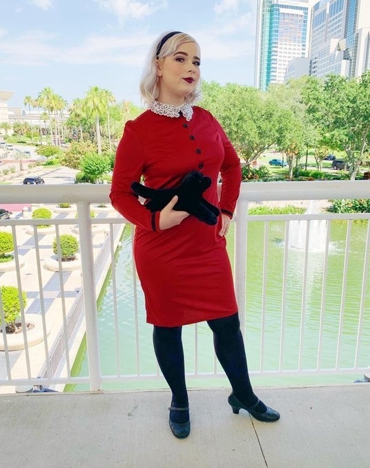 A woman wearing a dress with a lace collar and a headband, nearly matching the ones Sabrina wears on CAOS. 