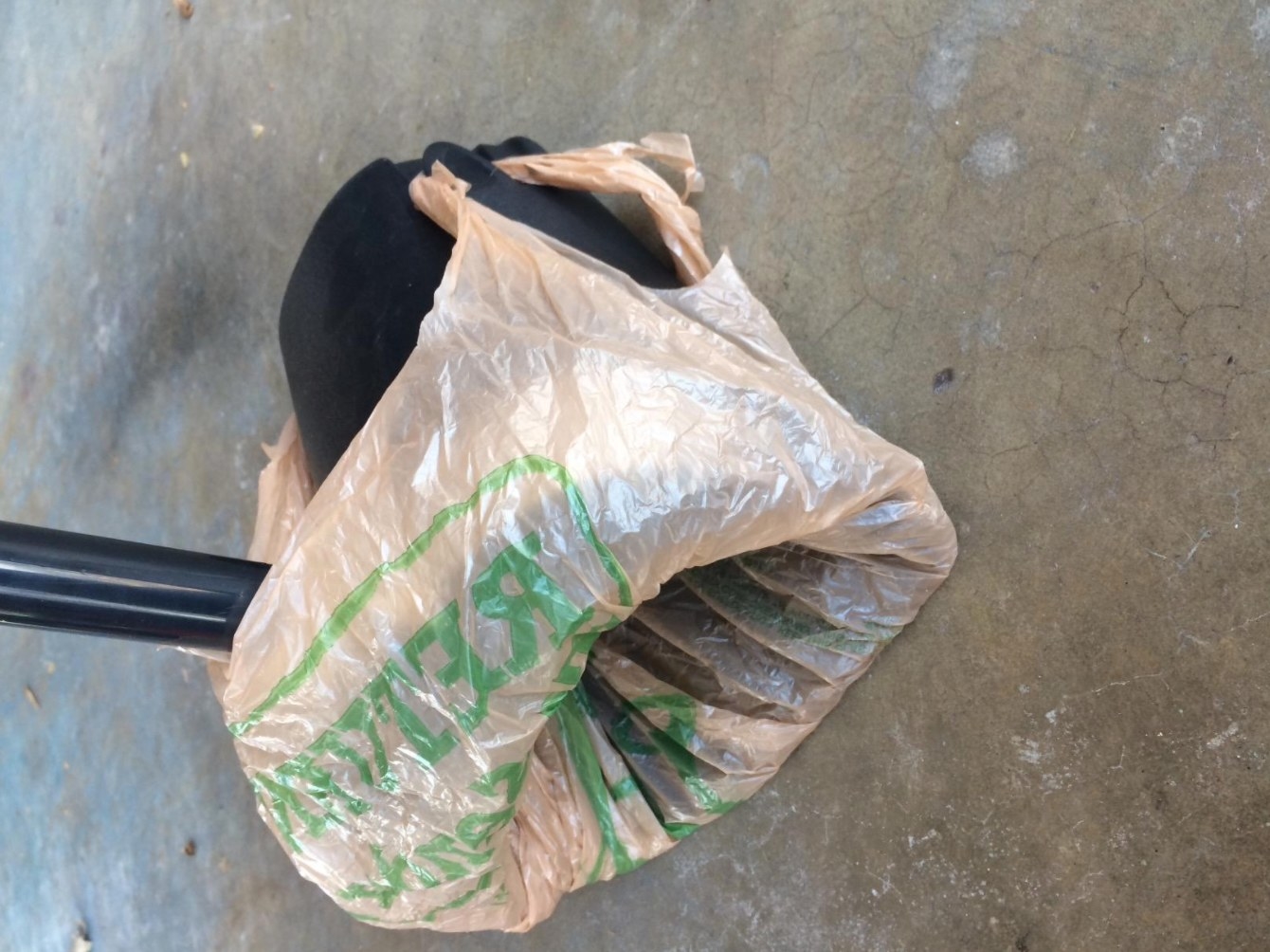 A reviewer&#x27;s image of the swivel bin and rake pooper scooper with a plastic bag