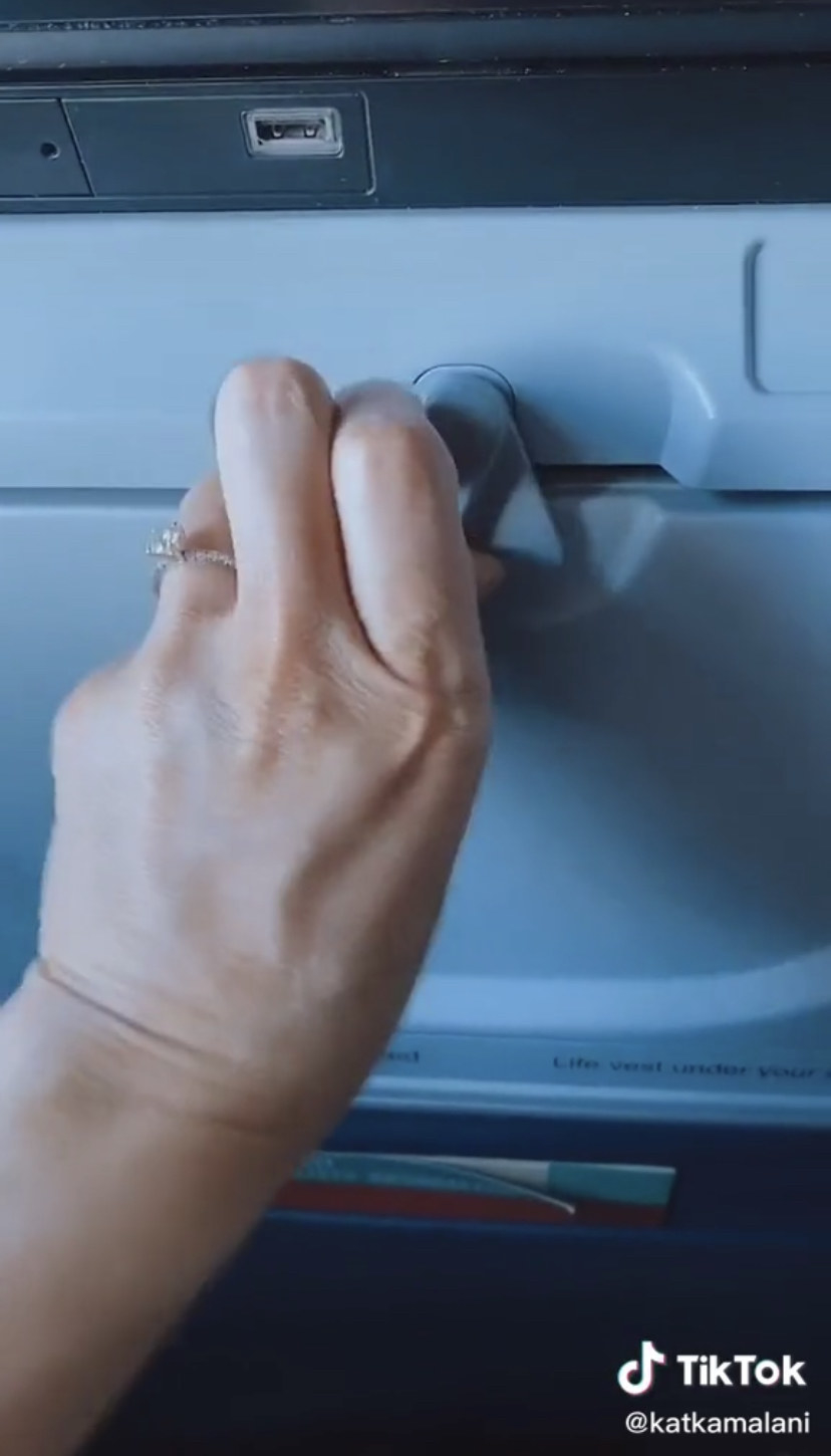A hand opening a tray table on an airplane