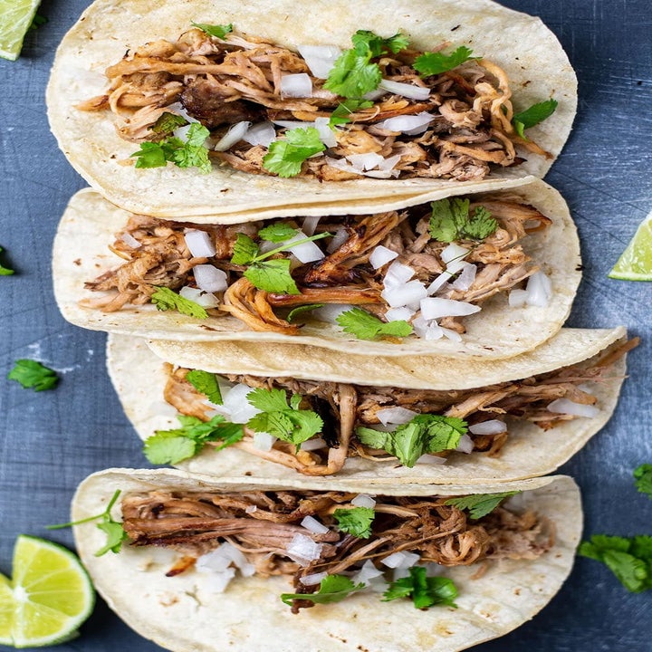 Four pork carnitas tacos with cilantro and onion.