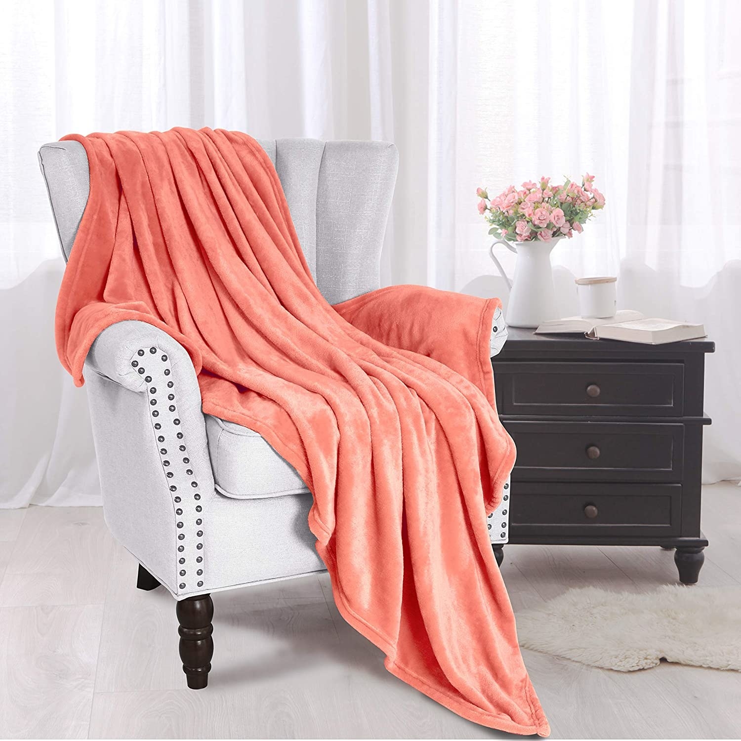flannel fleece throw blanket in coral draped over a chair next to a side table