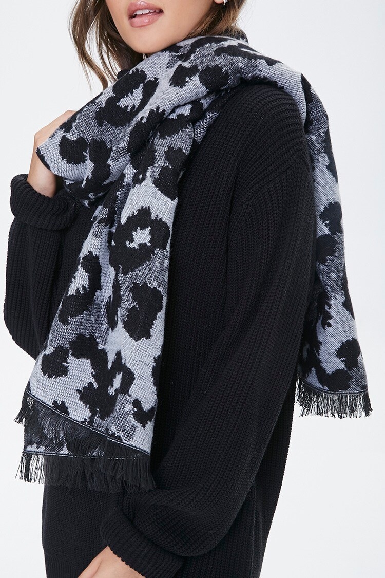 Model wears white, black, and gray leopard-print scarf with cozy black sweater