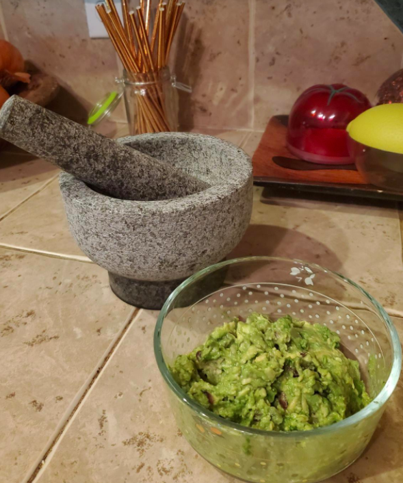 A reviewer photo of the mortar and pestle next to a bowl of guac they made with it