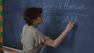 A teacher from the movie Clueless writing Have Fun on a blackboard