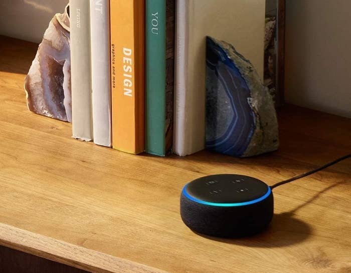 A smart speaker on a table beside books