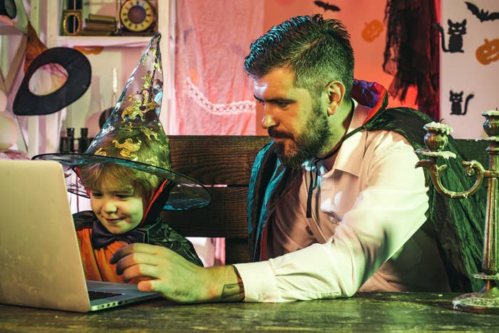 A father and son wear Halloween costumes and search their computer for a movie to watch.