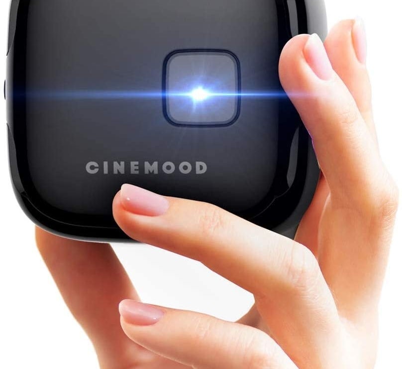 hand holding small black cube-shaped projector