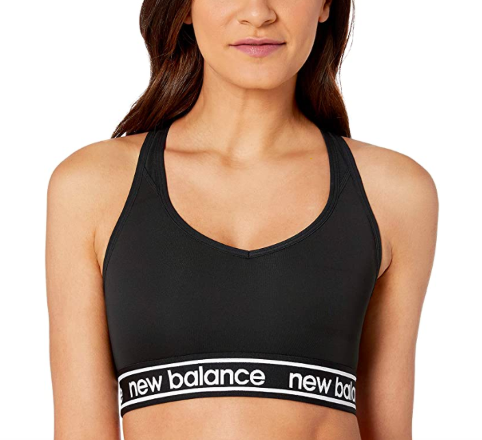 Model wears black racerback sports bra with white New Balance logo on the band