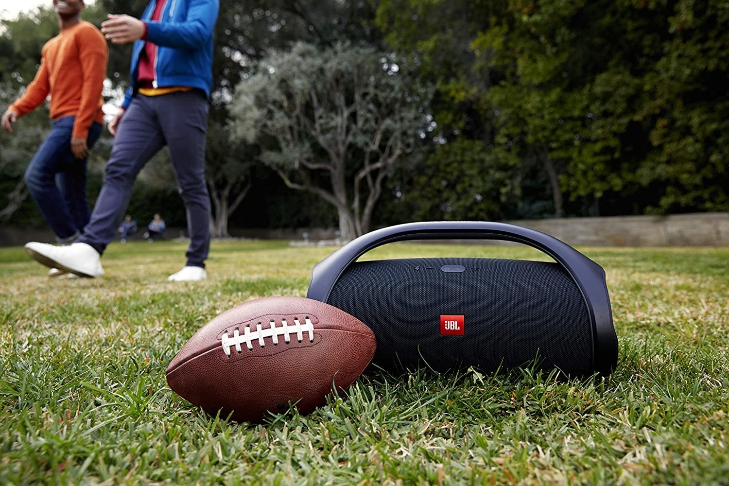 A large boombox speaker on the grass next to a football
