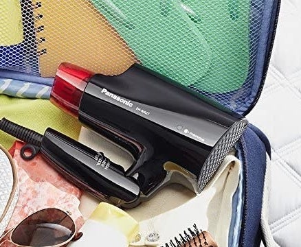 The compact hair dryer folded and placed inside an open suitcase