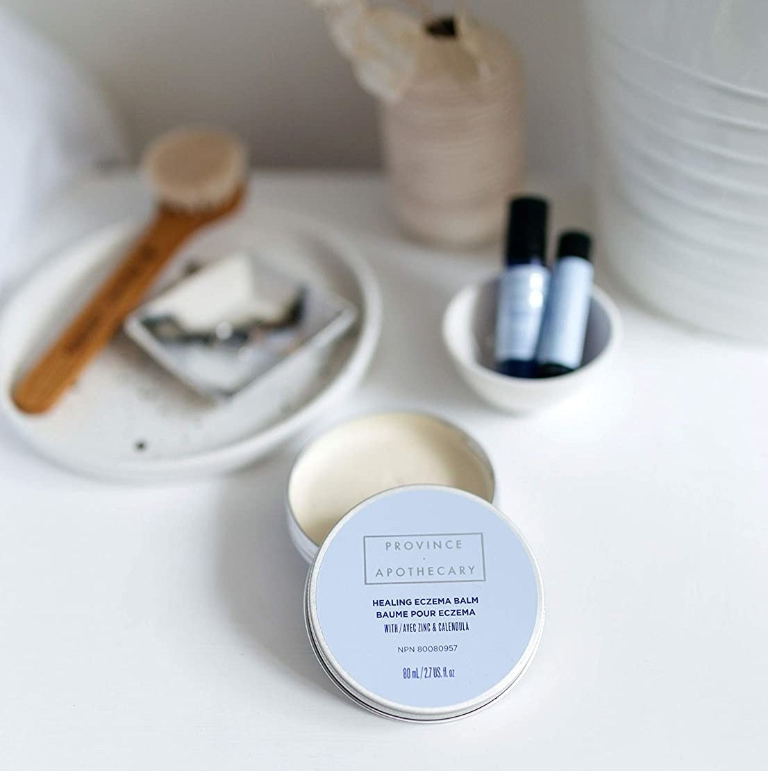 An open tin of the skin balm on a neatly arranged vanity