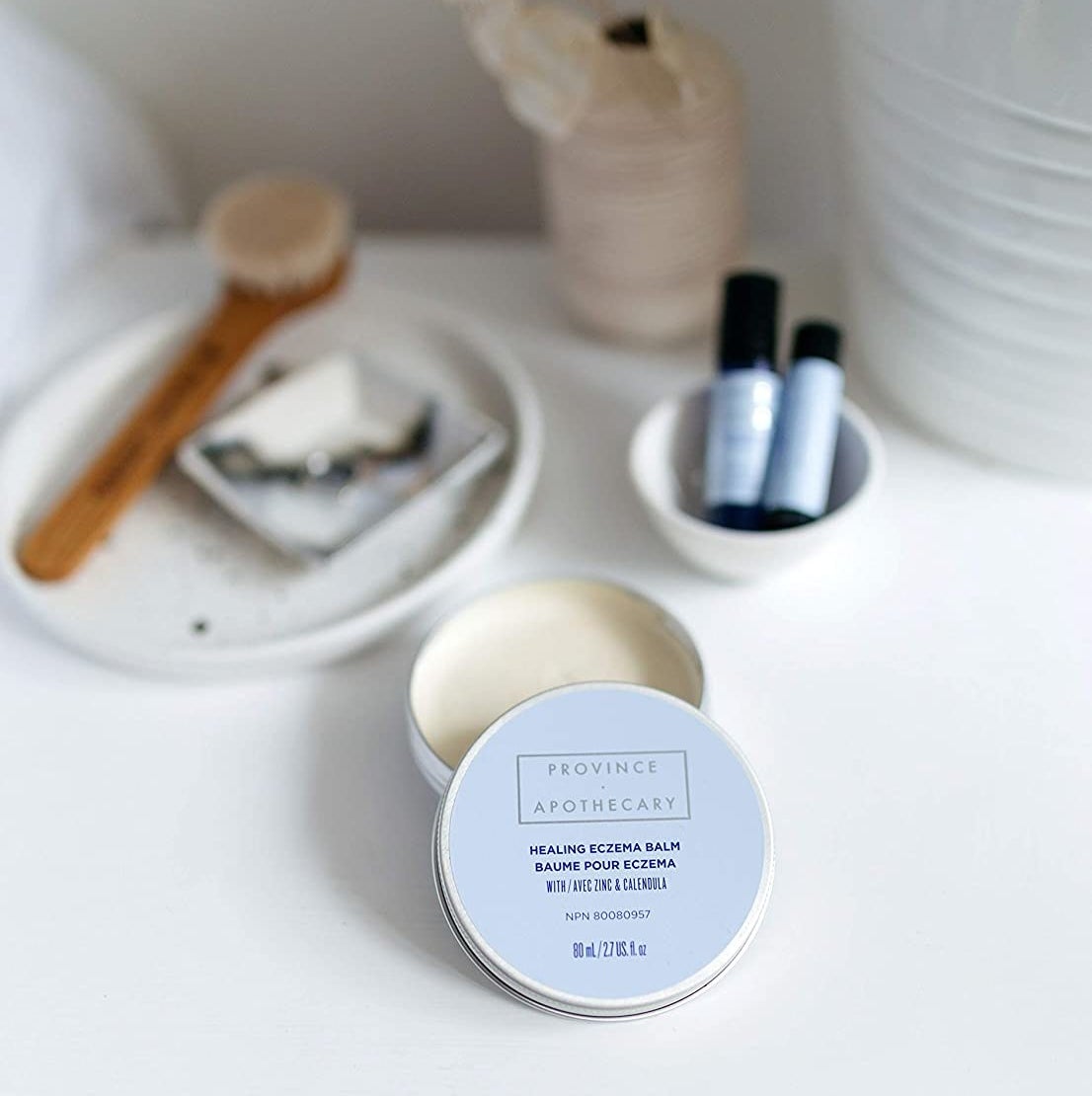 An open tin of the skin balm on a neatly arranged vanity