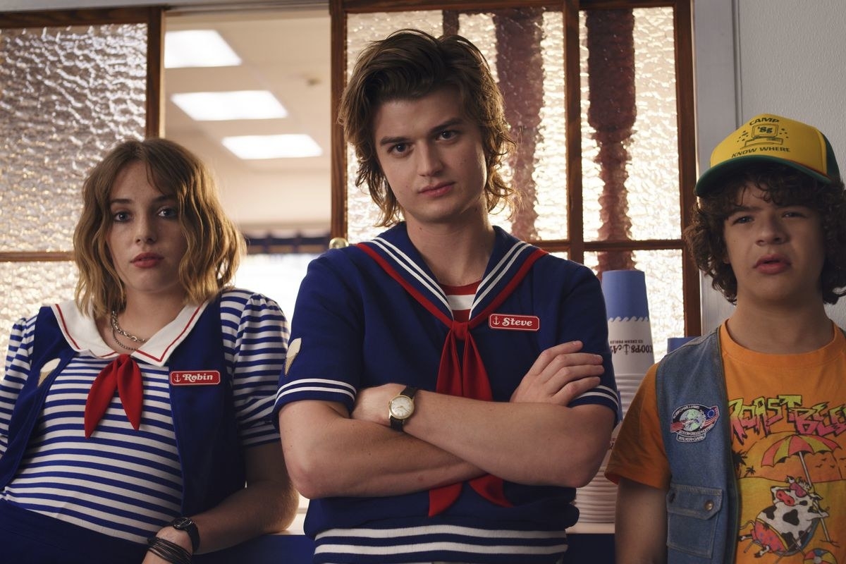 Robin, Steve and Dustin stand together in the ice cream store, looking skeptical 