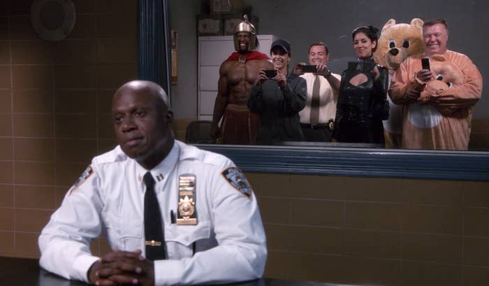 Captain Holt sitting with the 99 gang (minus Jake) behind him