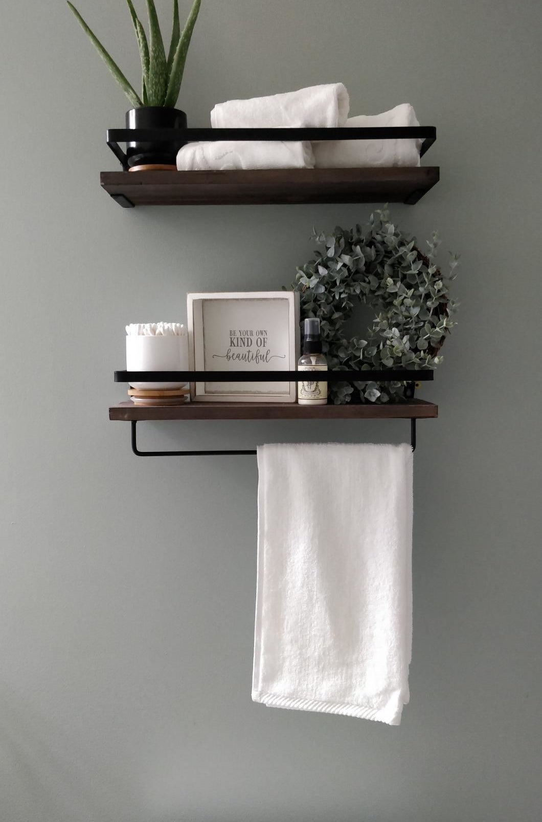 Reviewer pic of the two hanging shelves on the wall with towels and other bathroom items on them