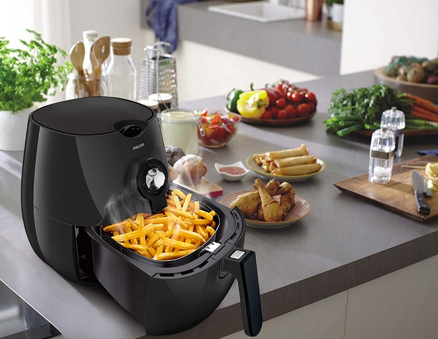 French fries being cooked in the air fryer. Other fried food items like fried chicken, spring rolls are kept next to it.