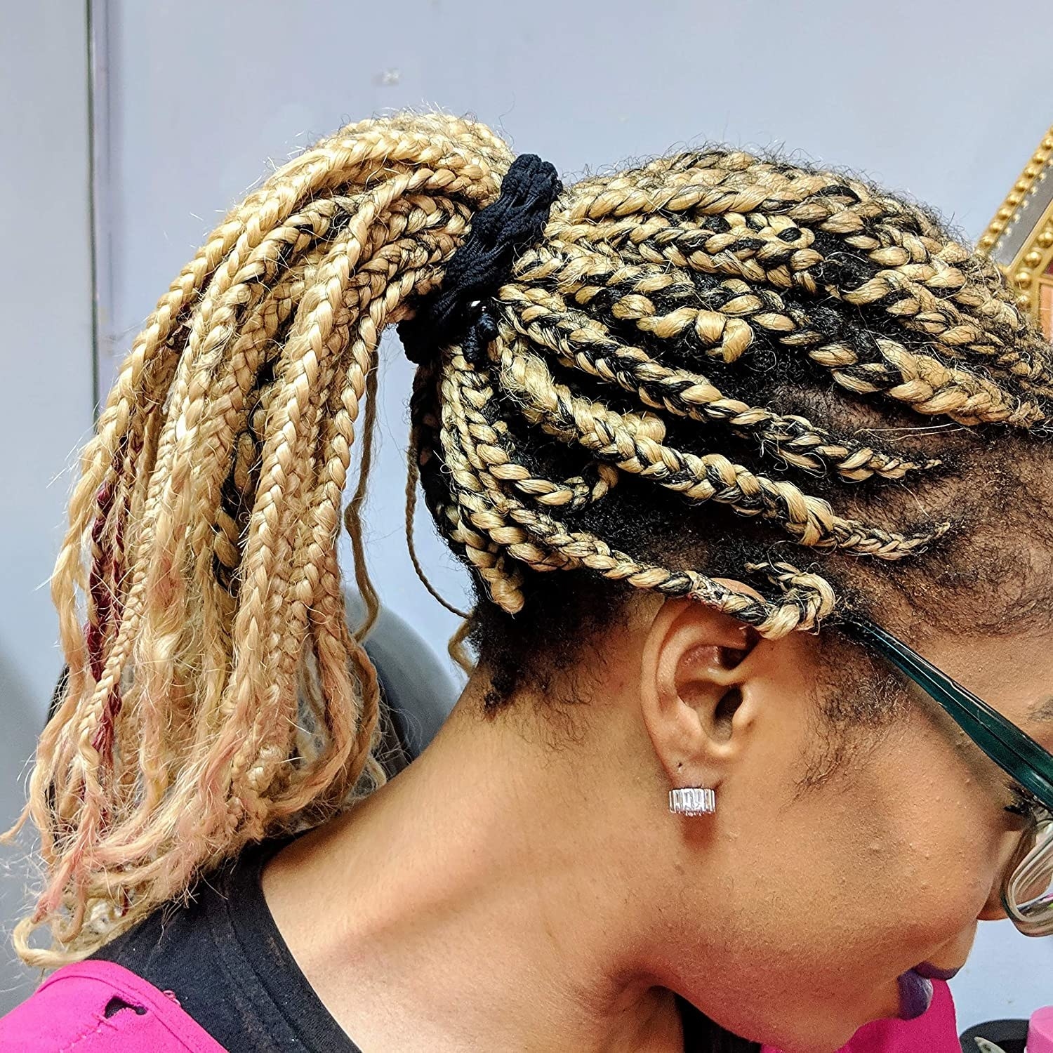 A person using the hair tie to hold their braided ponytail in place