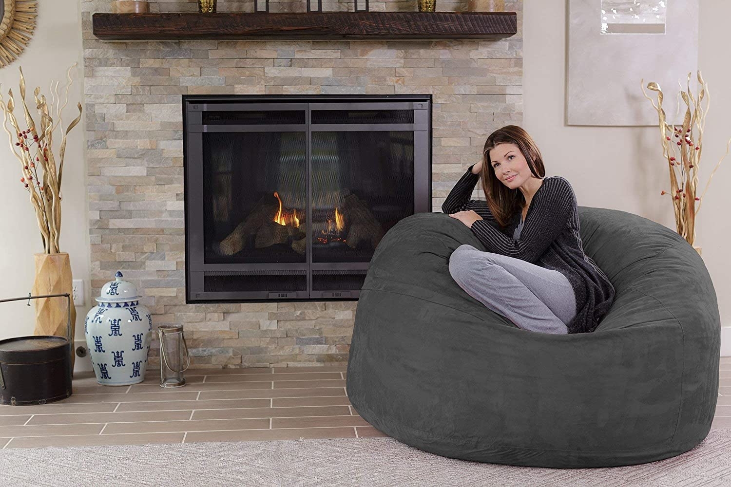 A person sitting in the bean bag chair by a fireplace