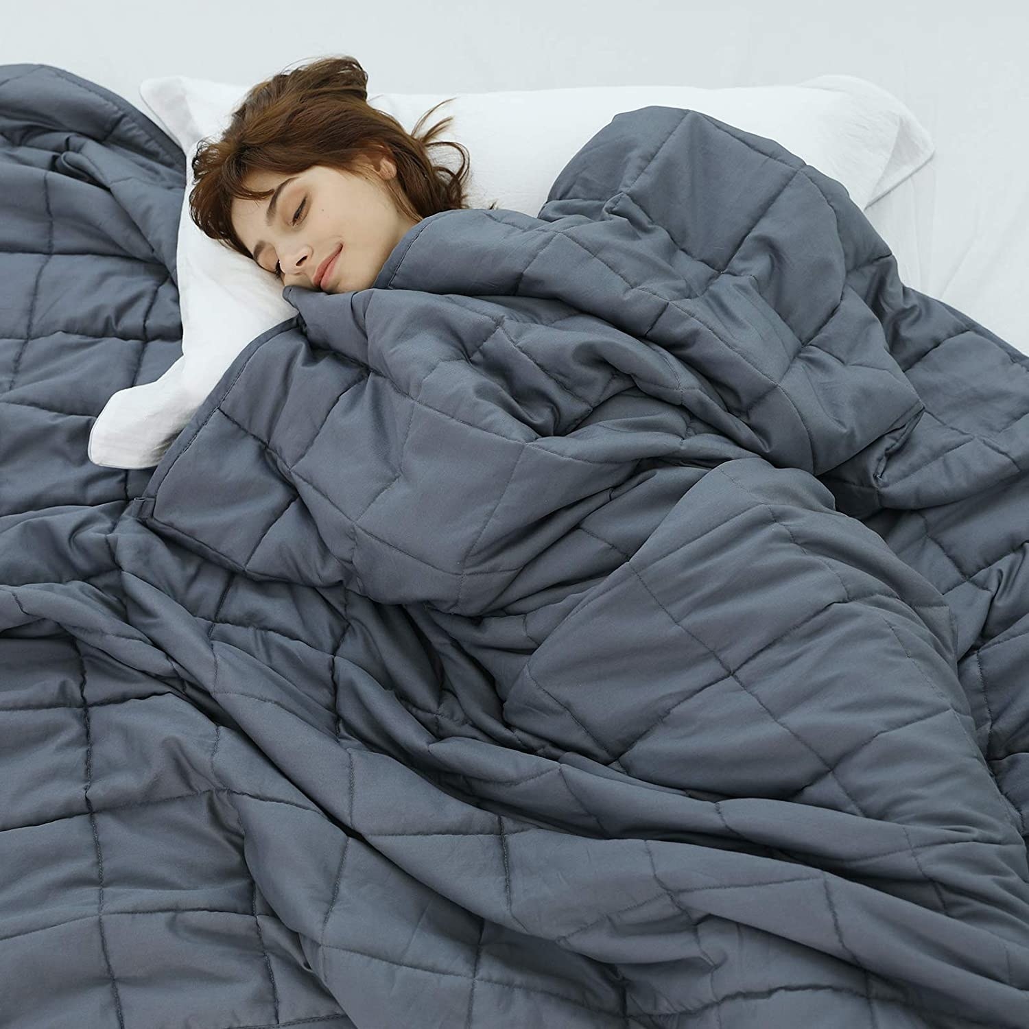 Model sleeping under the gray quilted blanket