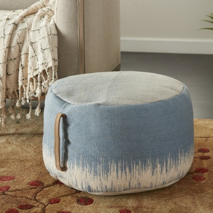 blue pouf ottoman with handle on the side and white design on the bottom